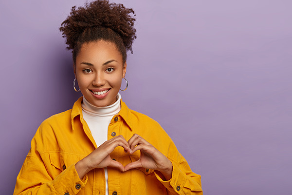 Afro American woman makes heart gesture because oral health and overall health are connected